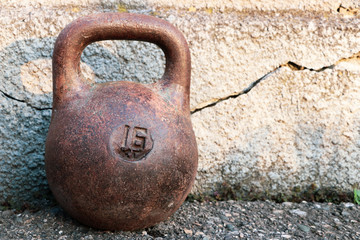 Naklejka na ściany i meble Old cast-iron sports weight on the wall background. Inventory for power sport of bodybuilding.
