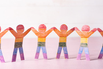 Rainbow paper human figures on color table. LGBT concept