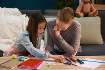 Cute girl with mother doing homework at home
