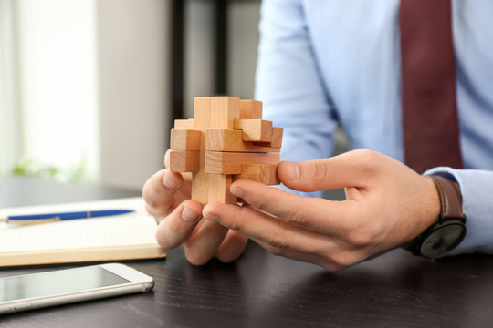 Young businessman with brain teaser at table in office