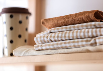 Stack of clean kitchen towels on wooden shelf