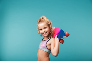 Smiling little sports girl playing with a skateboard