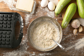 Ingredients and modern maker for preparing of squash waffles on wooden table