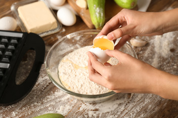 Woman making dough for squash waffles on wooden table