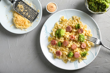 Plate with delicious pasta and sausage on grey table