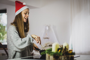 young woman with santa hat cooking at christmas time
