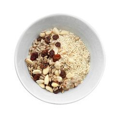 Tasty oatmeal with nuts and raisins in bowl on white background