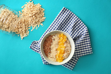 Tasty oatmeal with orange and sesame seeds on color table