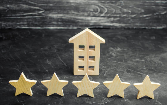 Five stars and a wooden house on a gray concrete background. The concept of the best housing, luxury apartments VIP class. The best service and universal recognition, a high score. Success.