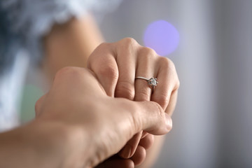 Obraz premium Man holding hand of his fiancee with engagement ring on finger, closeup