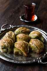 Turkish Midye Baklava ( Mussel Shape Baklawa ) with green pistachio Powder, Butter Cream and Traditional Tea in Silver Tray.