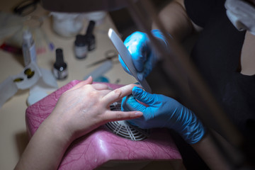 The girl on the manicure. The master covers the nail gel polish. Cosmetic procedures..