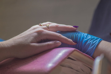 The girl on the manicure. The master covers the nail gel polish. Cosmetic procedures..