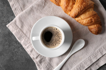 Cup of tasty aromatic coffee and croissant on table