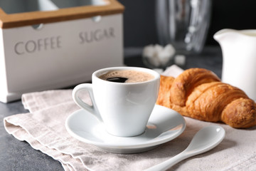 Cup of tasty aromatic coffee and croissant on table
