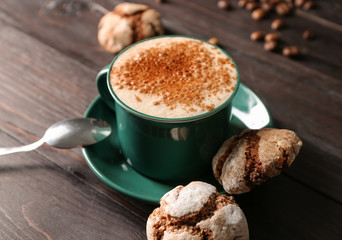 Mug of tasty aromatic coffee and cookies on dark wooden table