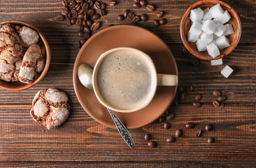Cup of tasty aromatic coffee with cookies and beans on wooden table