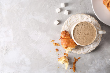 Obraz na płótnie Canvas Cup of tasty aromatic coffee with croissant on light table