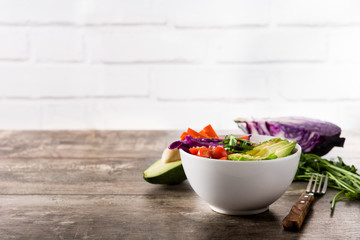 Vegan Buddha bowl with fresh raw vegetables and quinoa on wooden table. Copyspace

