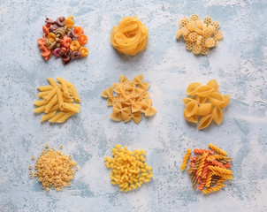 Fototapeta na wymiar Different types of raw pasta on color background