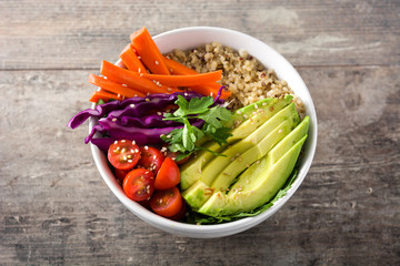 Vegan Buddha bowl with fresh raw vegetables and quinoa on wooden table. Close up

