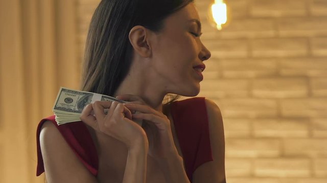 Beautiful lady taking money from sponsor, kissing dollars, selling love closeup