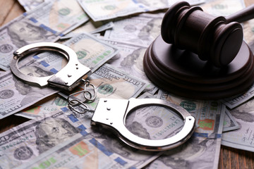 Judge's gavel with dollar banknotes and handcuffs on table. Corruption concept