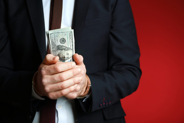 Businessman in handcuffs with bribe on color background. Corruption concept