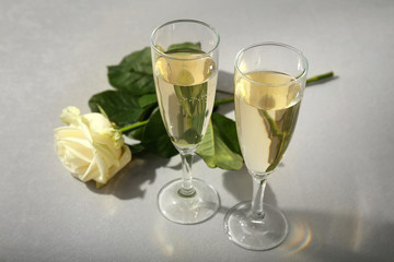 Glasses of champagne with flower on grey table