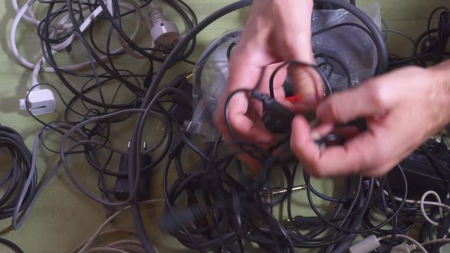 Man untangling tangled cables. Closeup.