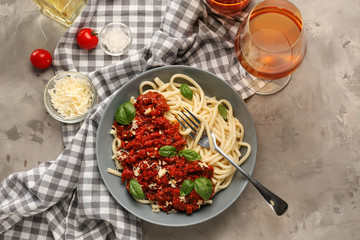 Plate with delicious pasta bolognese and wine on grey table