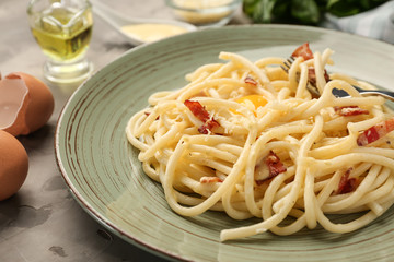 Plate with delicious pasta carbonara on grey table