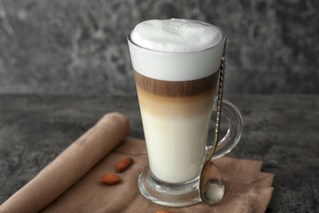 Glass cup of tasty aromatic latte on grey table