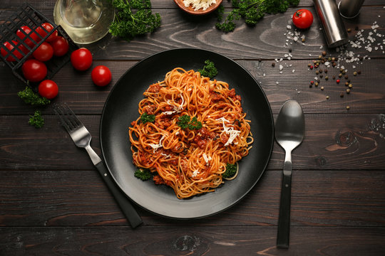 Plate with delicious pasta bolognese on dark wooden table