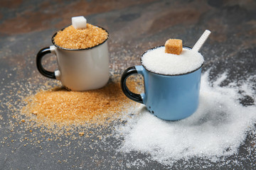 Metal cups with different sugar on grey table