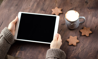 White tablet in hand. Wooden table, fragrant cocoa and cookies.