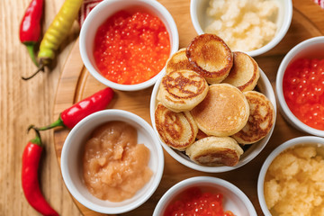 Set of tasty caviar with flapjacks on wooden table