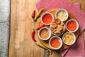 Set of tasty caviar with flapjacks on wooden table