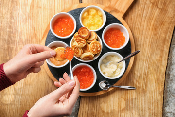Woman eating tasty red caviar with flapjack