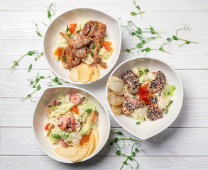 Plates with different tasty salads on white wooden table
