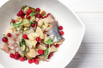 Plate with tasty fish salad on white wooden table