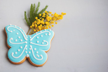 Blue gingerbread cookies in the shape of a butterfly with a sprig of yellow mimosa.