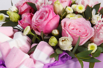 Flower arrangement bouquet of pink roses and colored marshmallows in a lilac box.