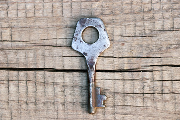 Old and rusty key on a wooden surface. View from above. Close-up.