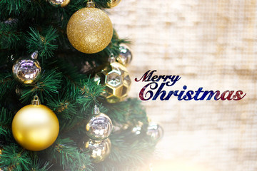 Shiny gold and silver christmas balls on white with pine tree and merry christmas text