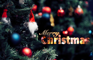 Closeup of red bauble hanging from a decorated Christmas tree. Happy new year concept with merry christmas text