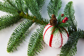 White ball with cones for the Christmas tree and fir tree on a light background, close-up