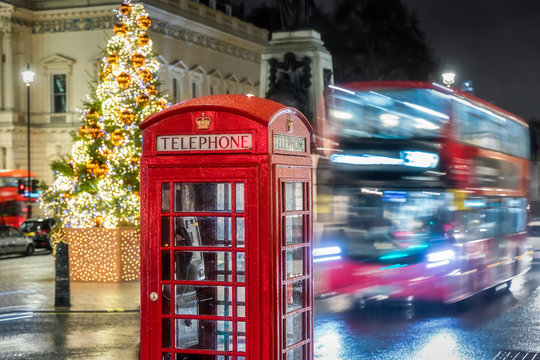 Weihnachten in London: rote Telefonzelle und roter Doppeldecker Bus in London vor einem festlich geschmückten Weihnachtsbaum