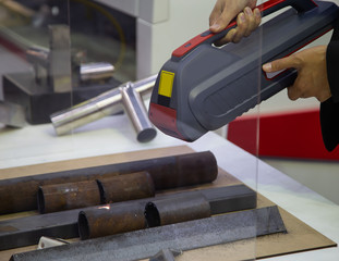 Industrial technician use handheld laser cleaning gun to remove rust from tube. Industrial metalworking. © Itsanan