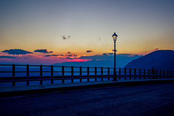 evening twilight suburb outskirt environment near European village in mountain highland place with street lantern dark silhouette and empty road on sunset sky background, copy space